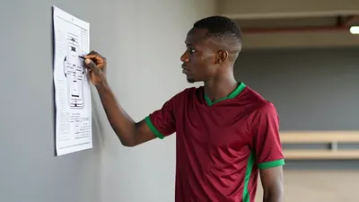 A tight, waist-up shot of a 25-year-old, 5'10" African player with a lean build, wearing a plain, dark red and green...