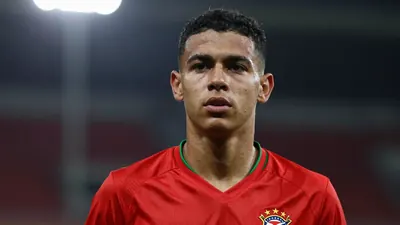 A 20-year-old Brazilian soccer player, with a lean build and short black hair, wearing a solid red jersey, photographed...