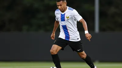 A 20-year-old French midfielder, wearing a white jersey with a blue stripe, a black pair of shorts and black boots, with...