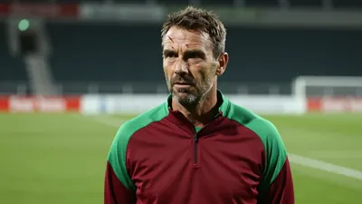 A 35-year-old, ruggedly-built, Le Mans FC assistant coach with a strong jawline and a distinctive scar above his left...