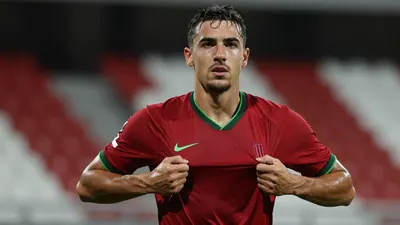 Mid-30s Le Mans FC midfielder, muscular, waist-up, drenched in sweat, eyes focused, pulling a dark red jersey with green...